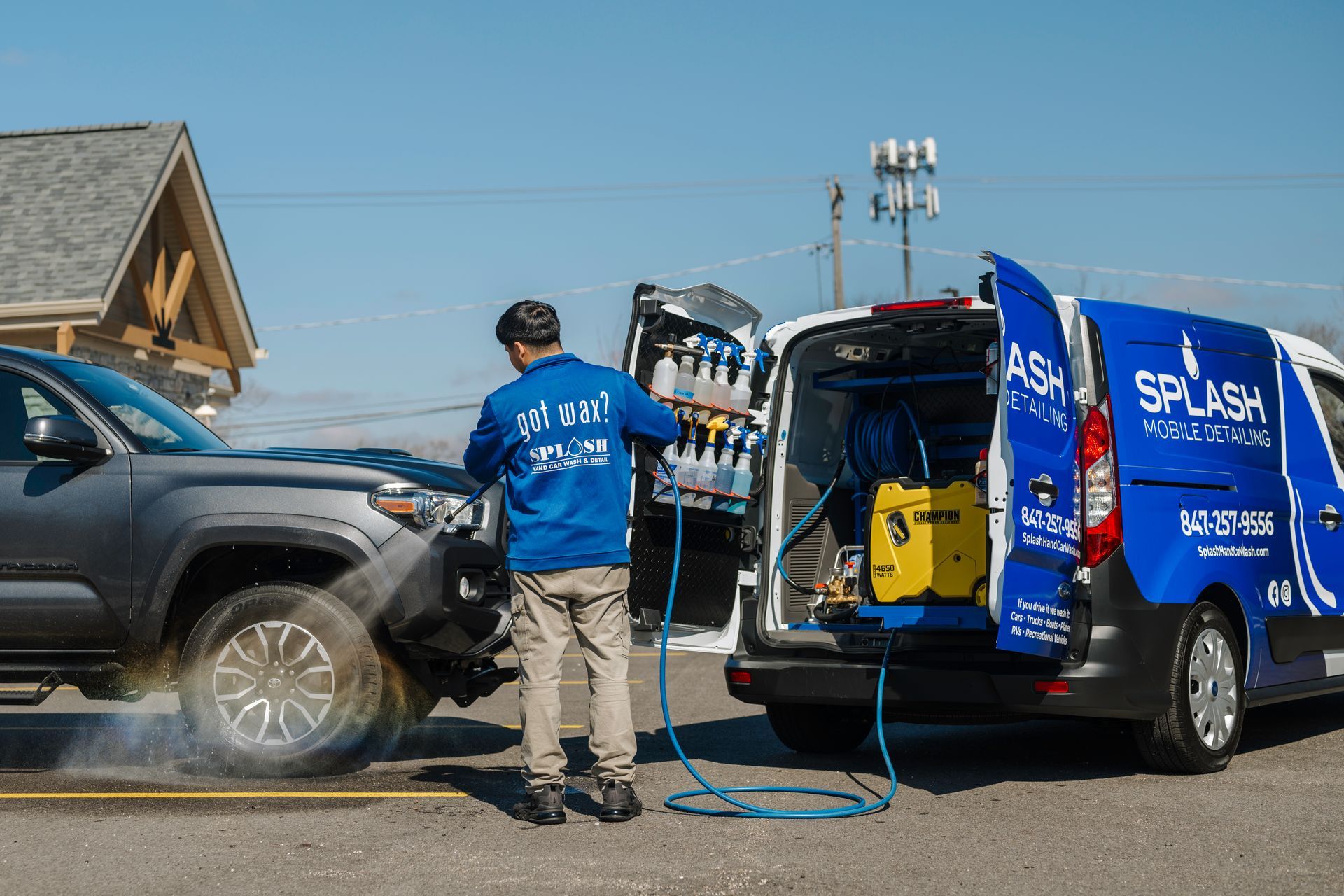 A man is washing a car next to a van.