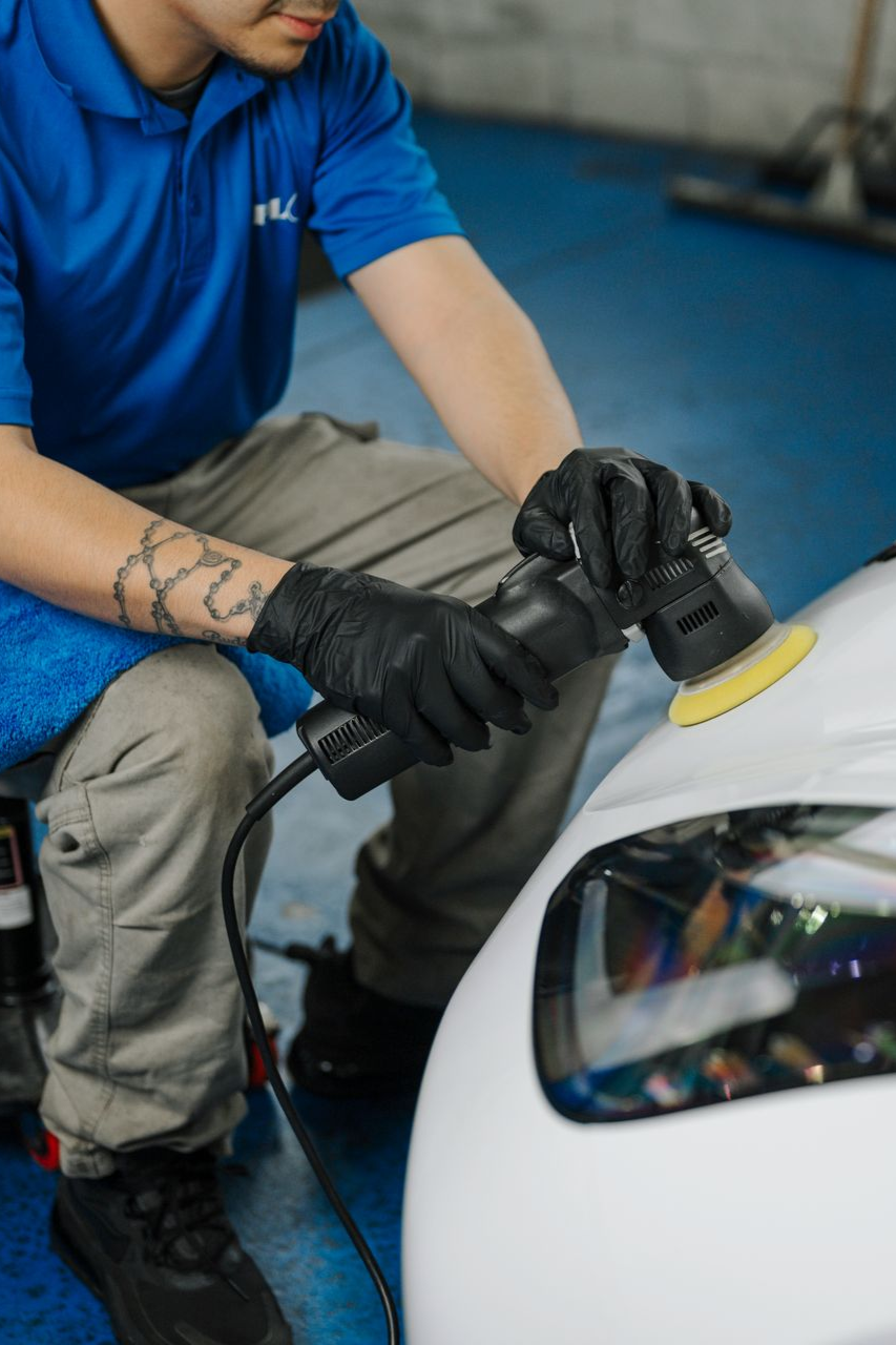 A man is polishing the front of a white car.