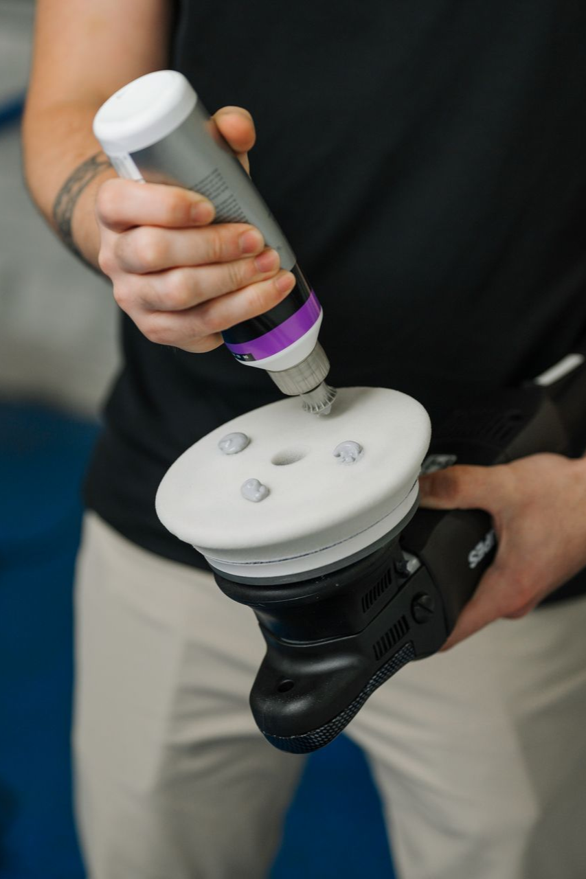 A man is holding a polisher and a bottle of polish.