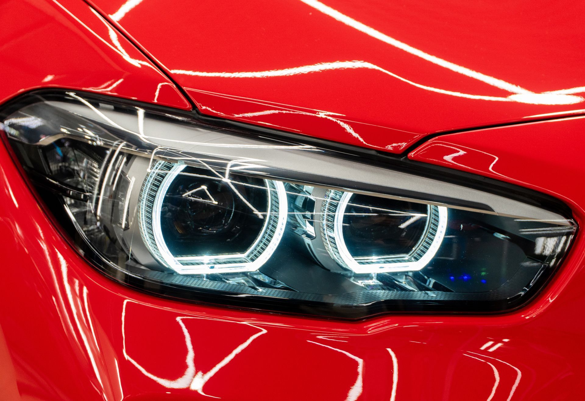 Close-up of a red car headlight with bright LED rings