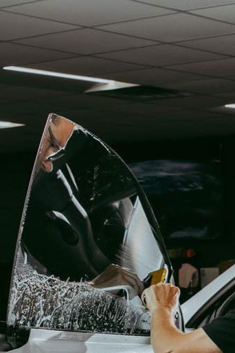 A man is applying tinted glass to a car window.