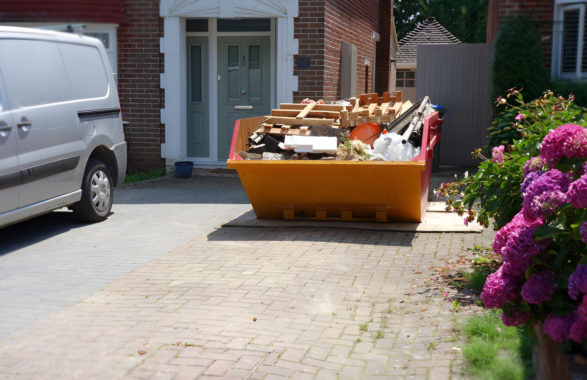 Orange Skip Filled With Construction Debris on a Brick Driveway — Skip Bin Hire Sunshine Coast in Kin Kin, QLD