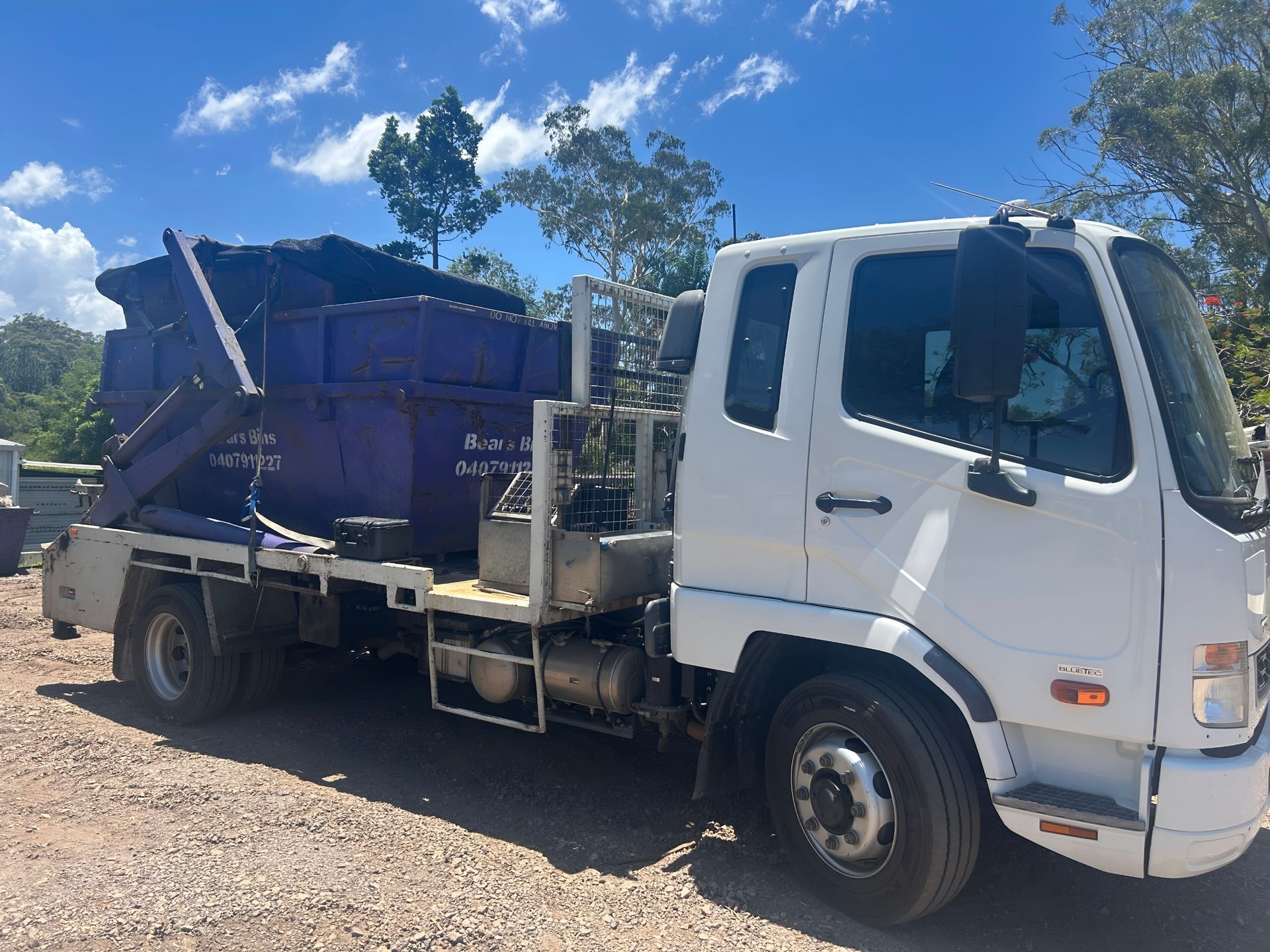 White Truck With a Purple Dumpster on the Back, Parked Outdoors — Skip Bin Hire Sunshine Coast in Coolum, QLD