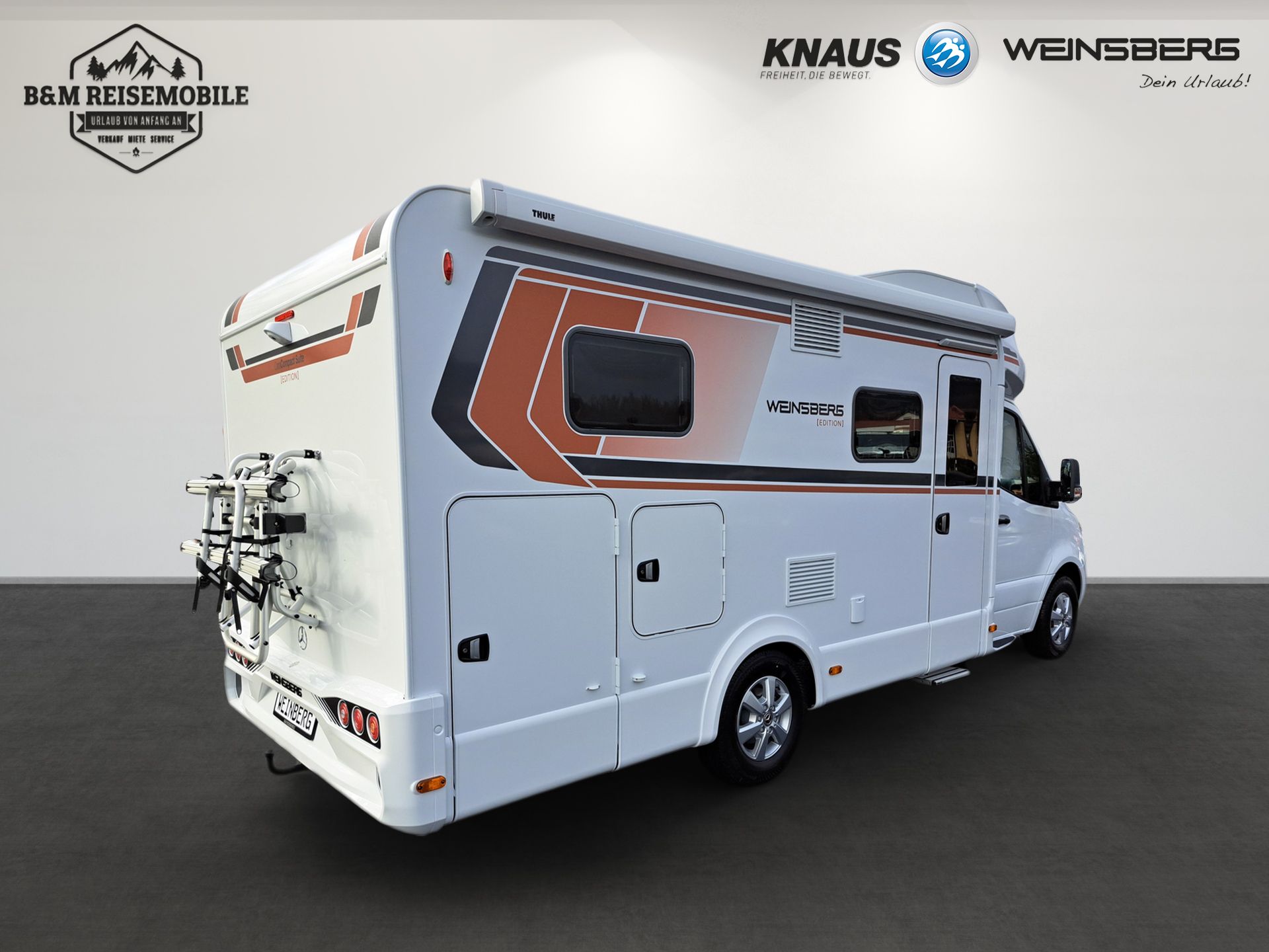Weißer Knaus-Campingbus mit orangefarbenen Grafiken, aufgenommen in einem Studio vor weißem Hintergrund.