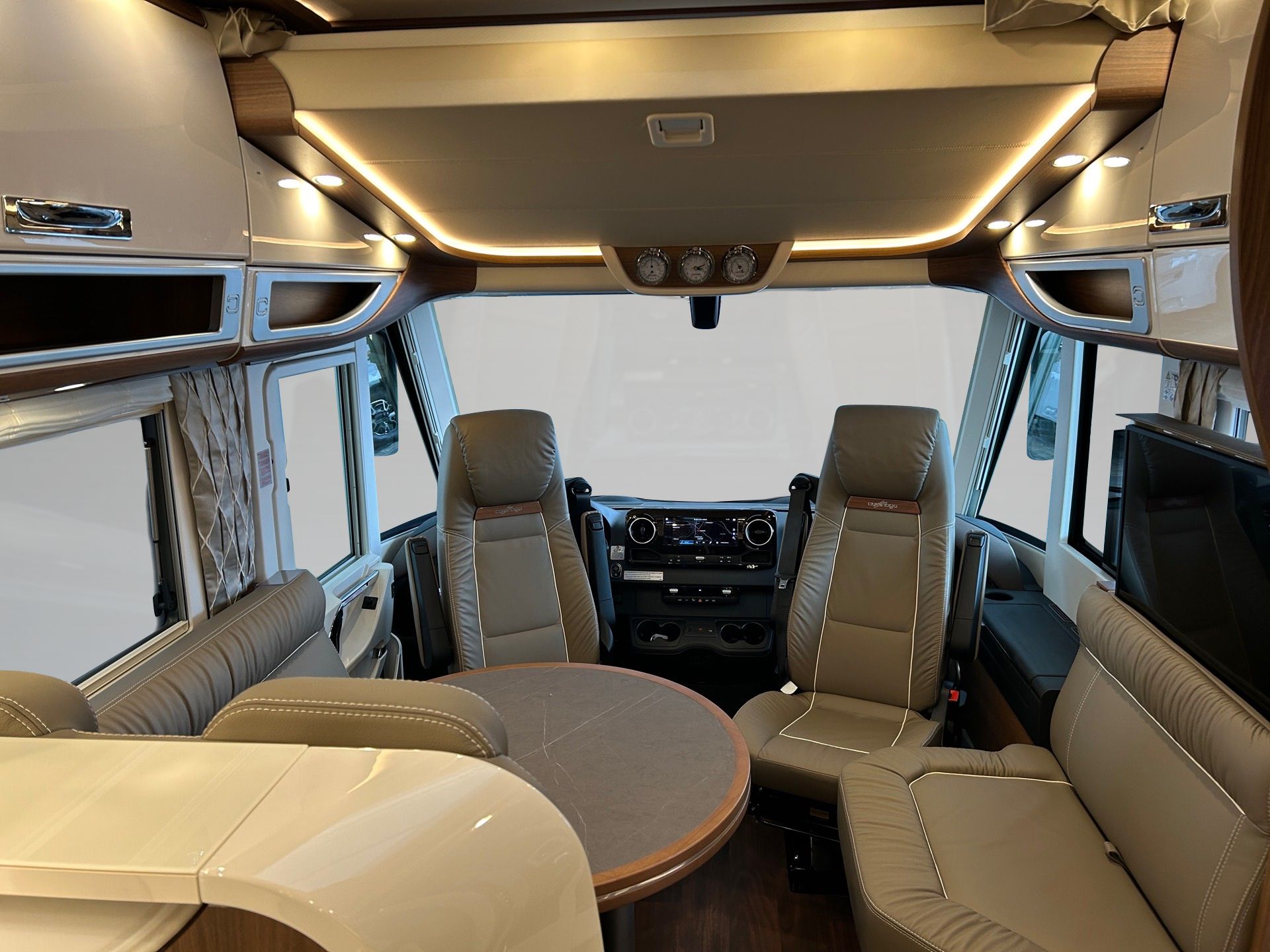 Luxuriöses Wohnmobil-Interieur mit beigen Ledersitzen, rundem Tisch und Deckenbeleuchtung