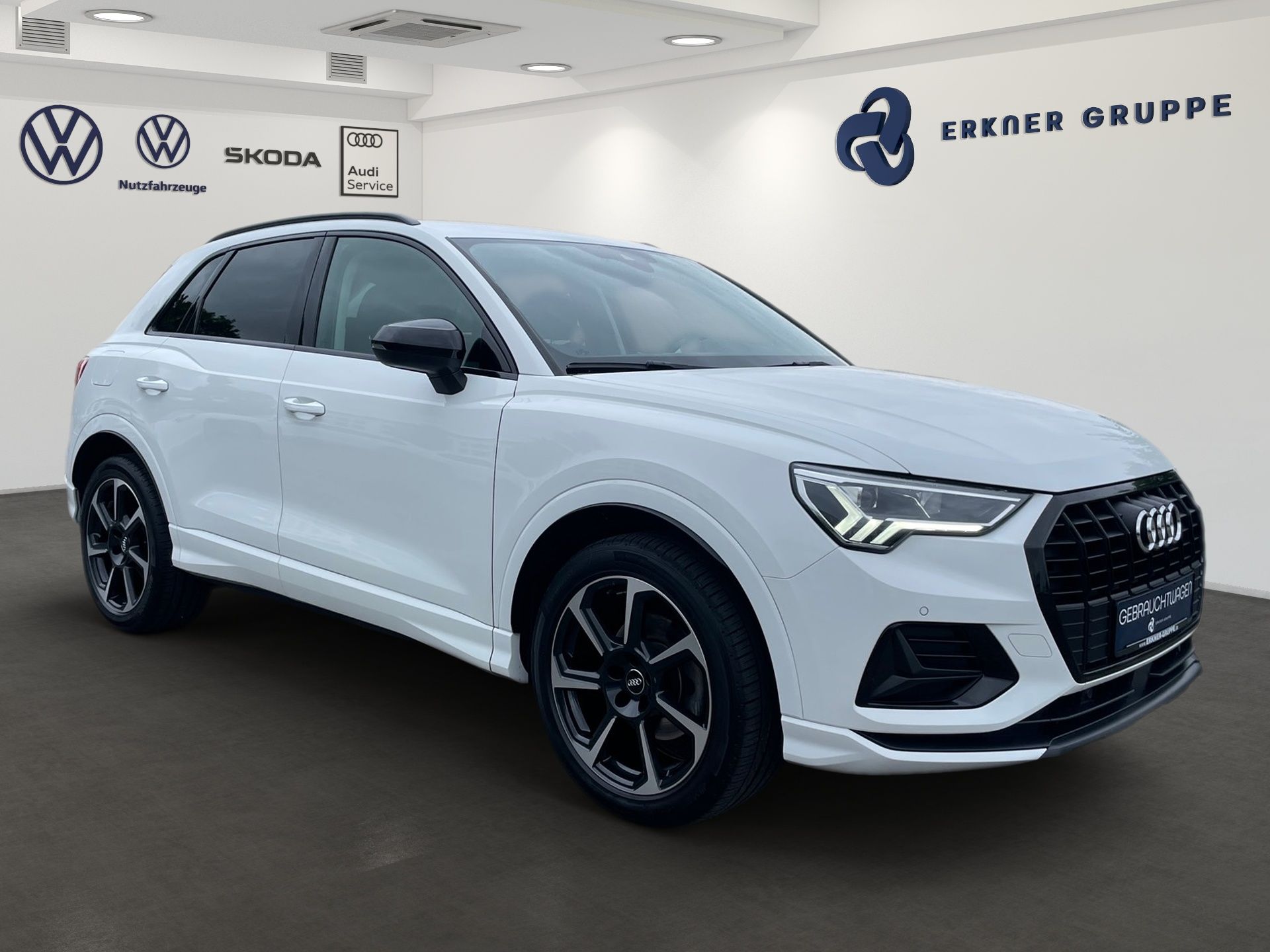 Ein weißer Audi Q3 steht in einem digitalen Ausstellungsraum.