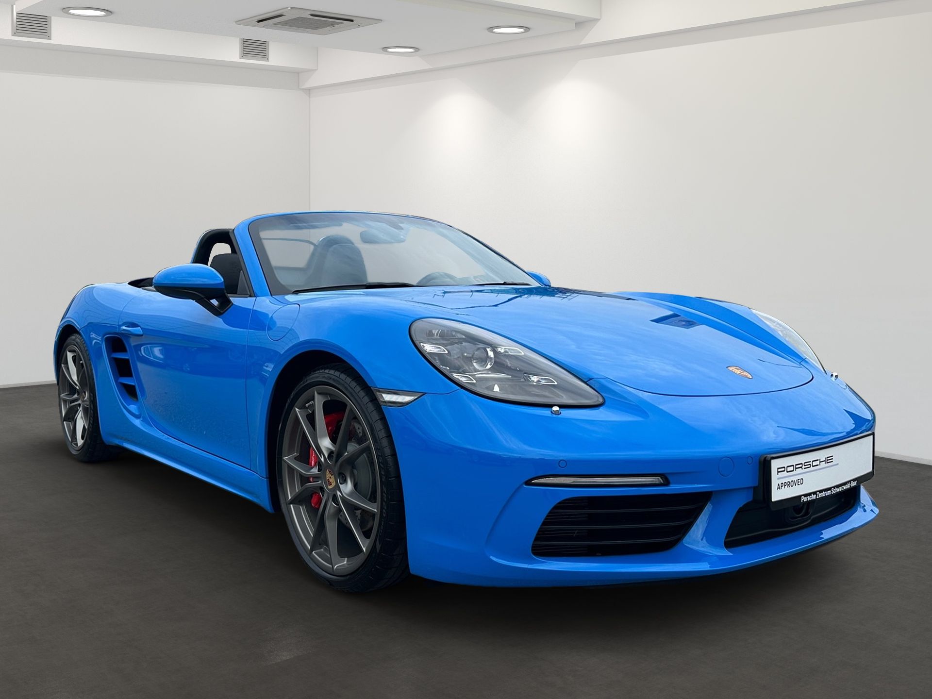 Ein blauer Porsche Boxster steht in einem digitalen Ausstellungsraum.