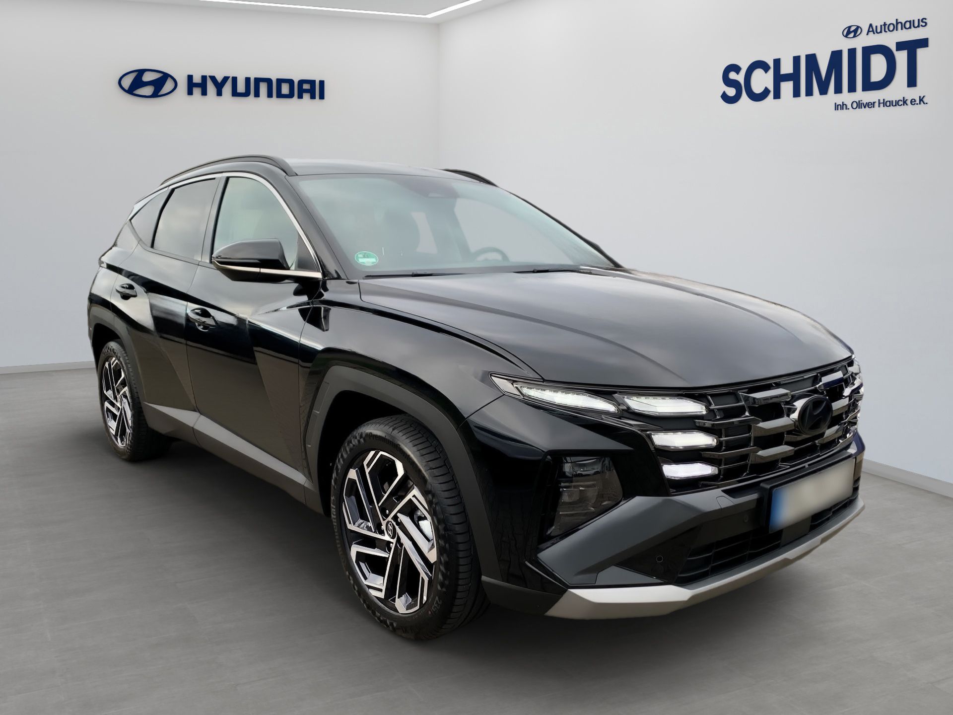 Ein schwarzer Hyundai SUV parkt in einem Ausstellungsraum mit Hyundai- und Schmidt-Logos an der Wand.