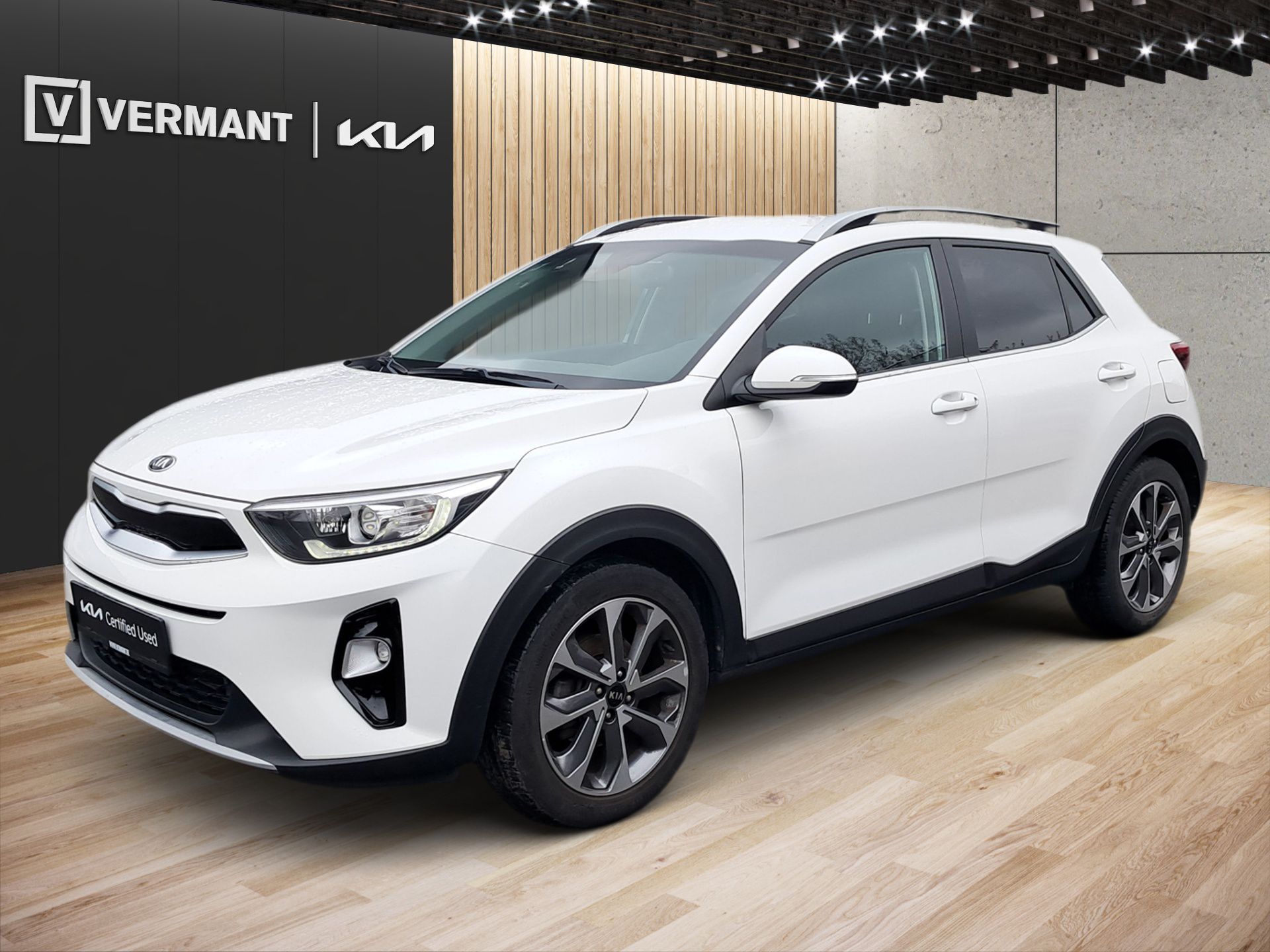 Ein weißer Kia SUV wird in einem Ausstellungsraum mit Holzboden und VERMANT-Logo an der Wand präsentiert.