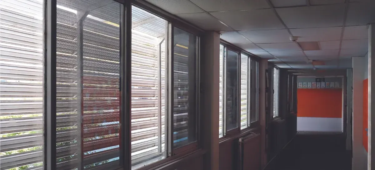 A long hallway with lots of windows and blinds.