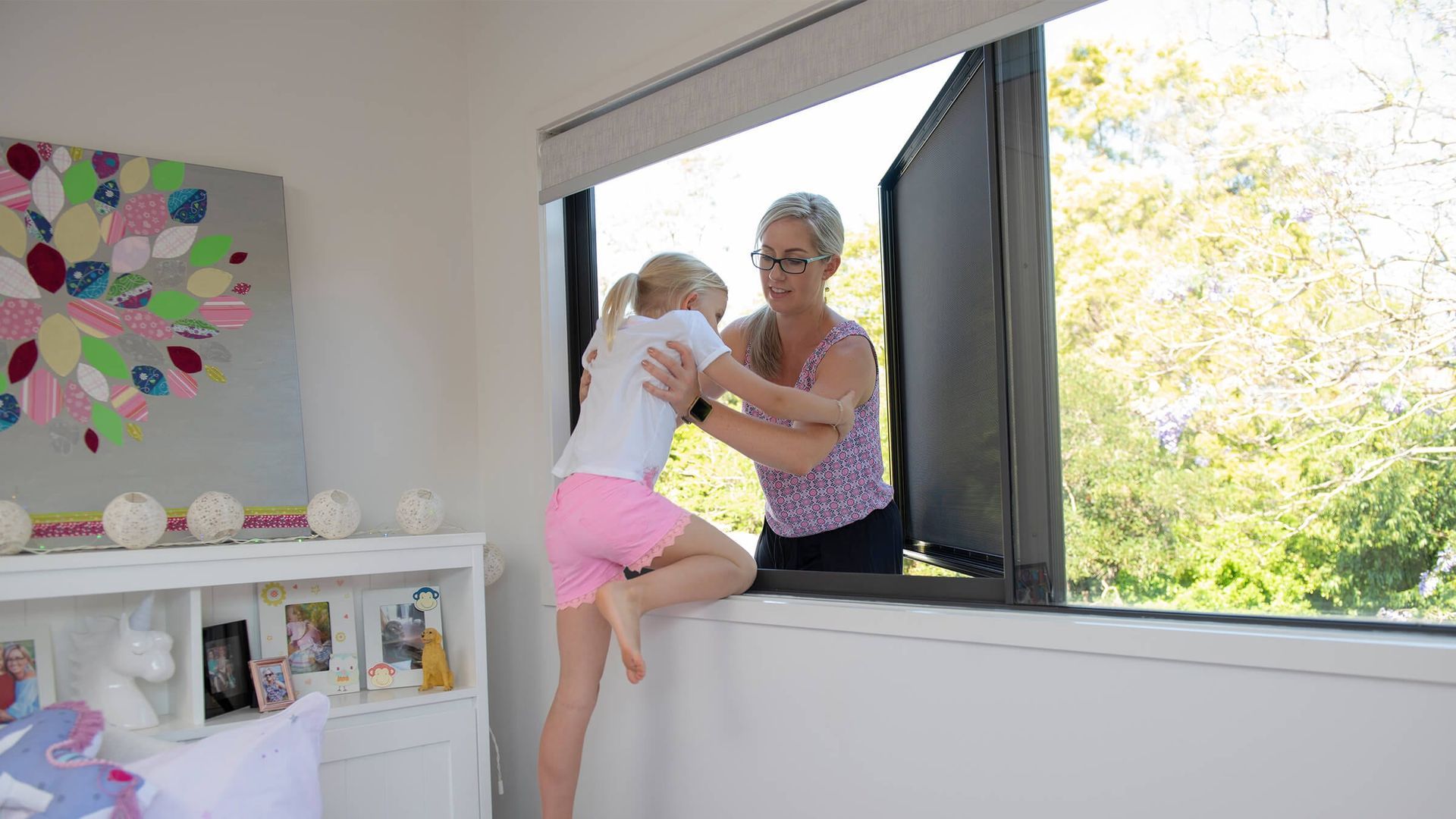 A woman and a little girl are looking out of a window.