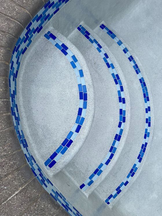 Curved blue mosaic tile patterns on a light gray concrete surface
