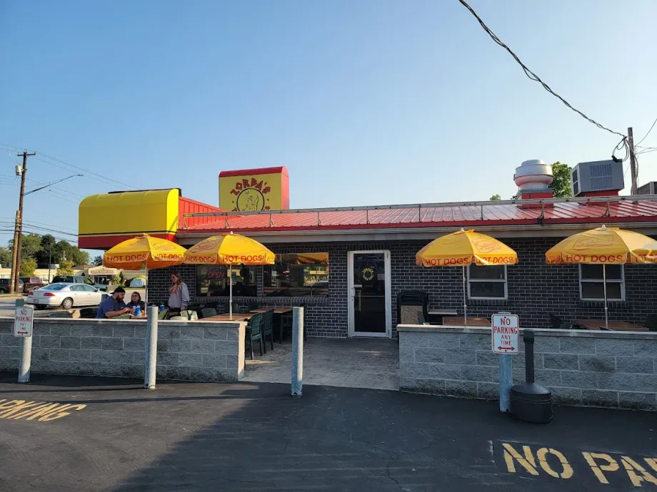 A diner with yellow umbrellas and sign; people sit outside.