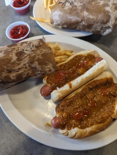 Two chili dogs, fries, and a burger on a plate with ketchup.