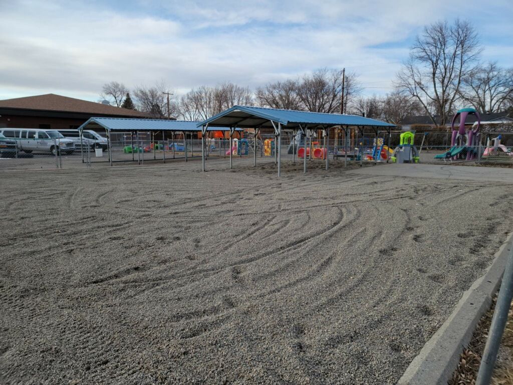 A parking lot with a playground in the background.