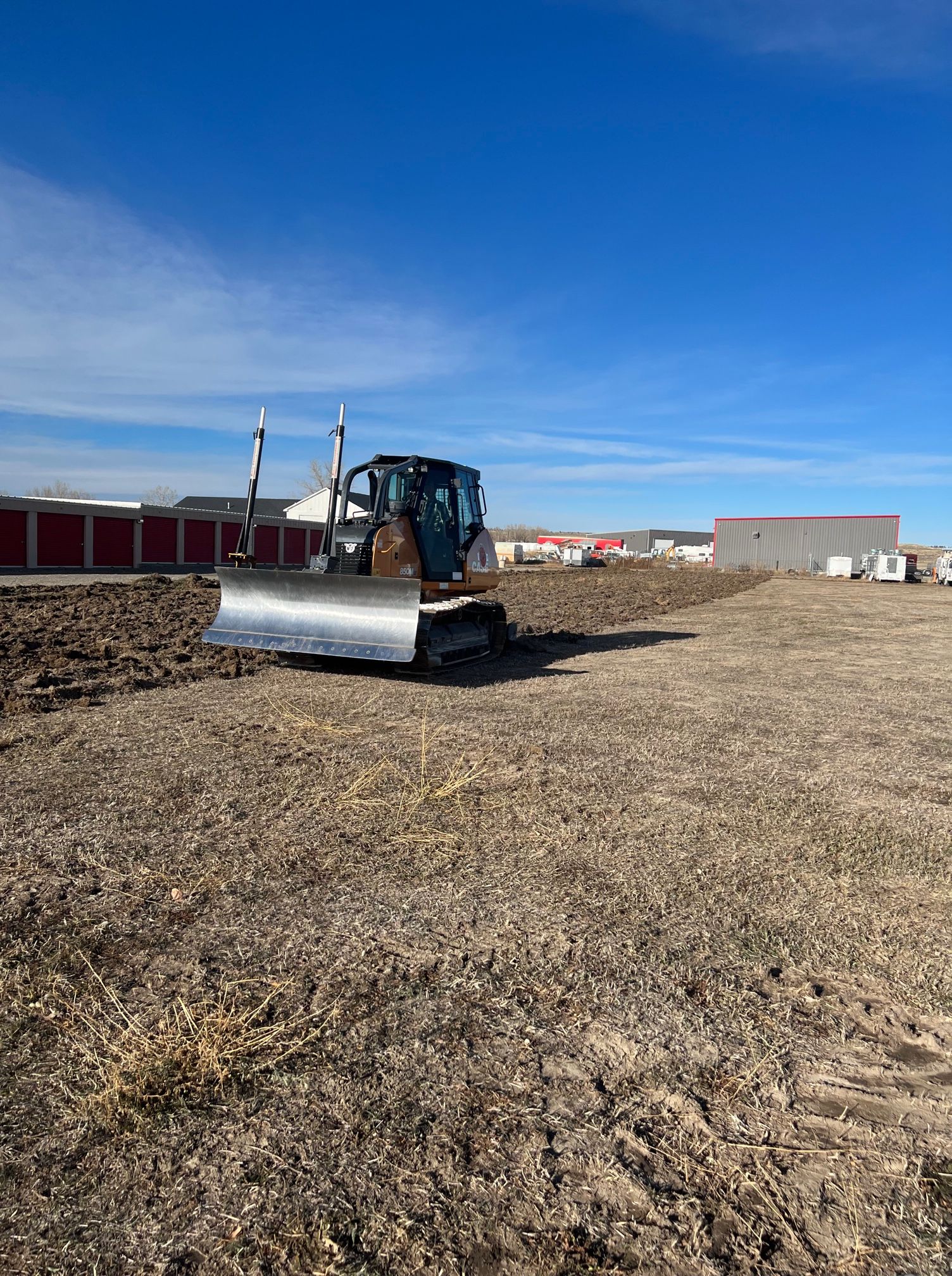 A bulldozer is sitting in the middle of a dirt field.