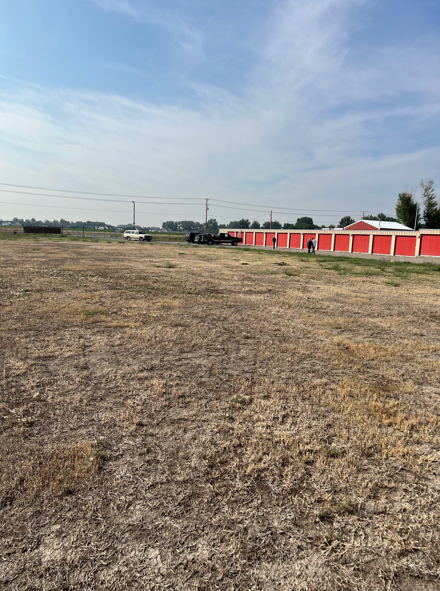 A large dry field with a red building in the background.