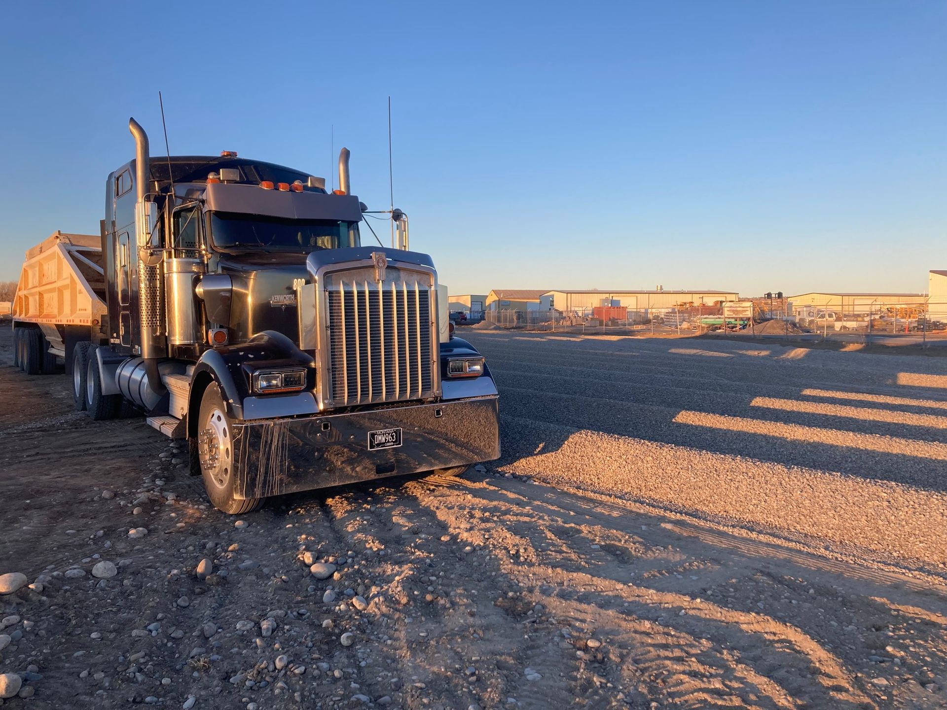 A large semi truck is parked in a dirt lot.