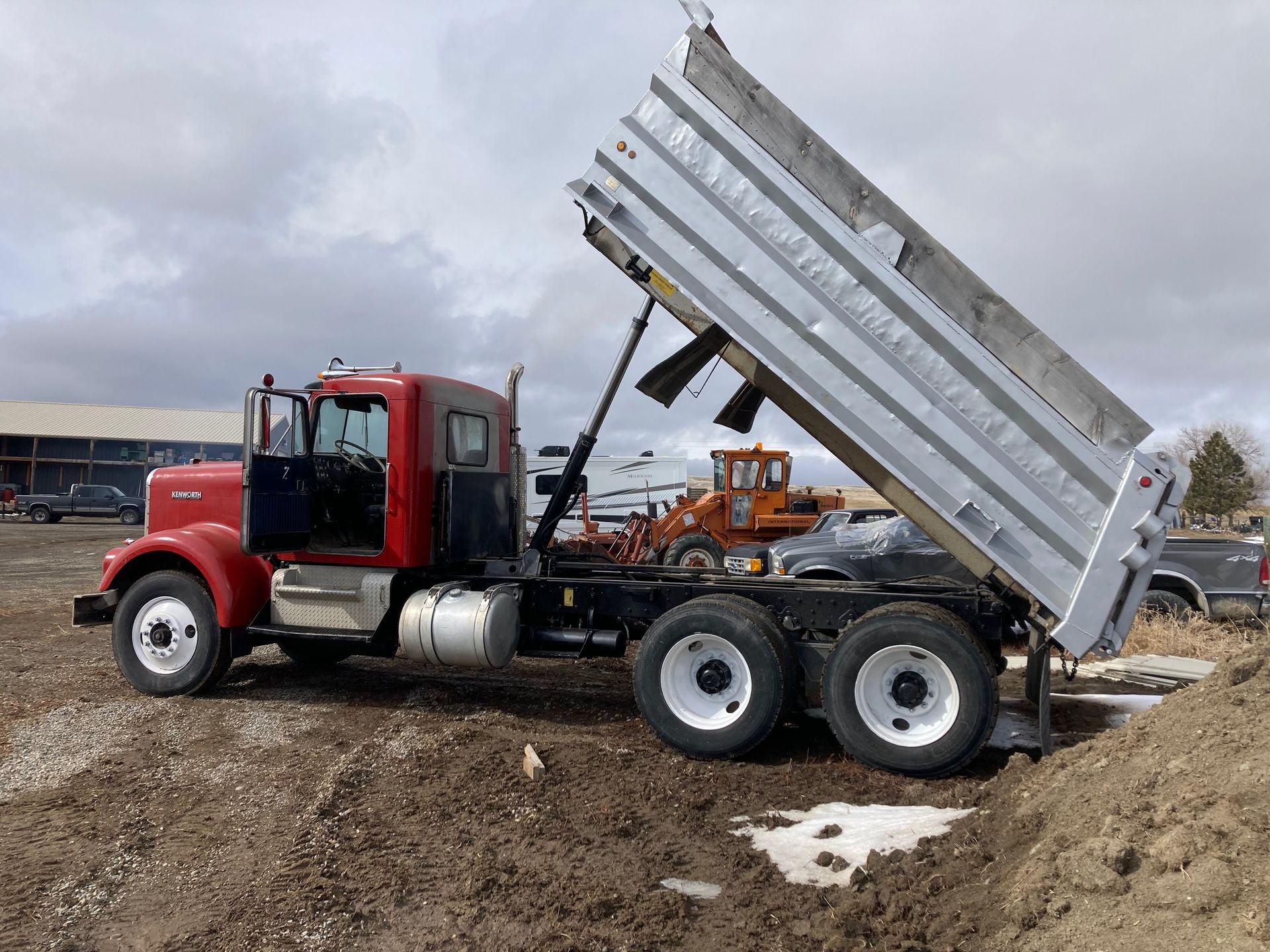 A red dump truck is sitting on top of a pile of dirt.
