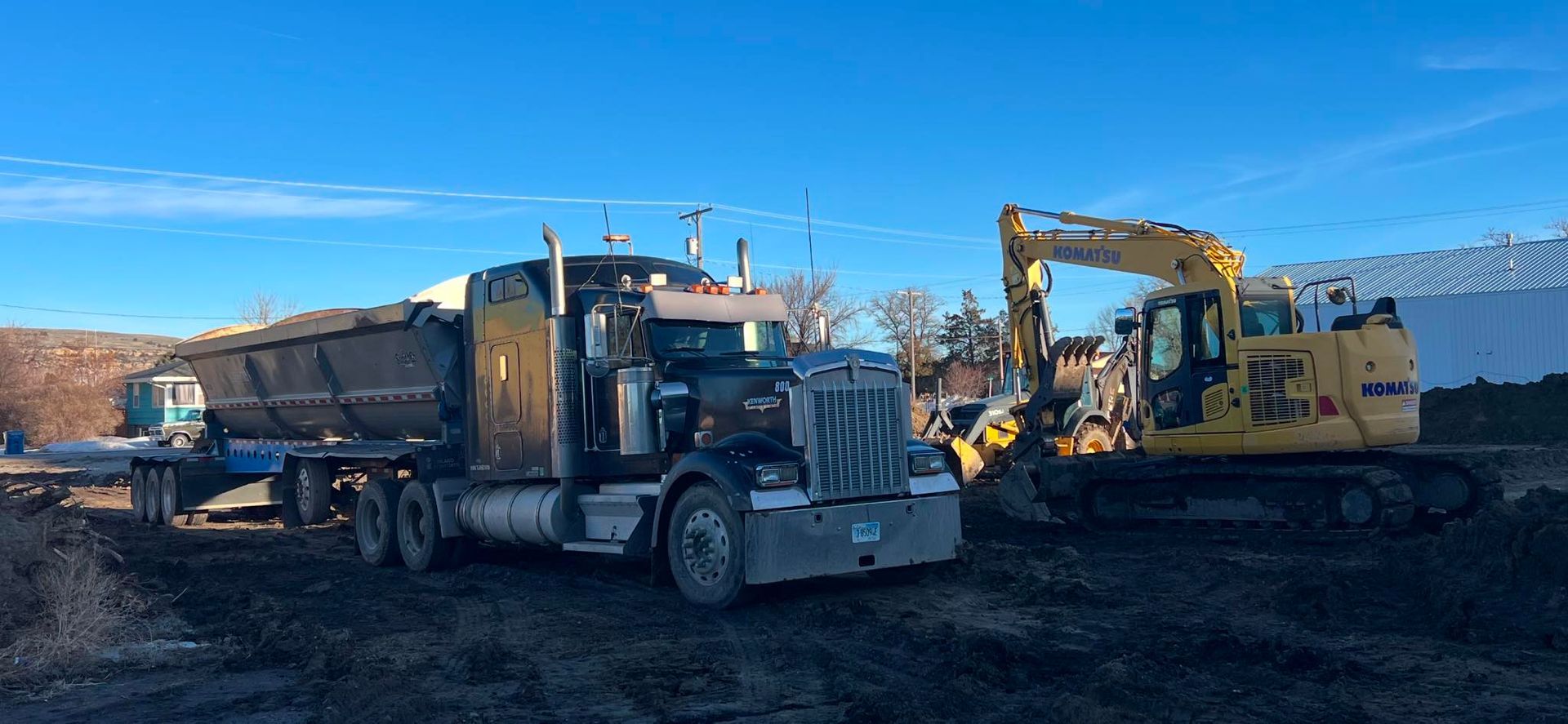 A dump truck and an excavator are parked in a field.