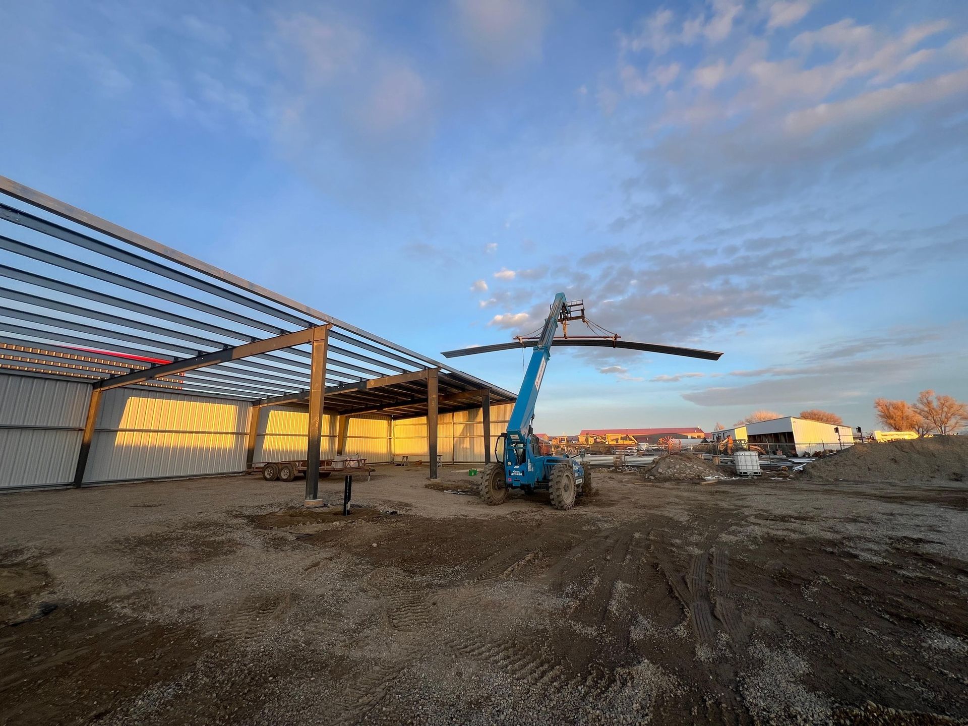 A crane is lifting a piece of metal in front of a building under construction.