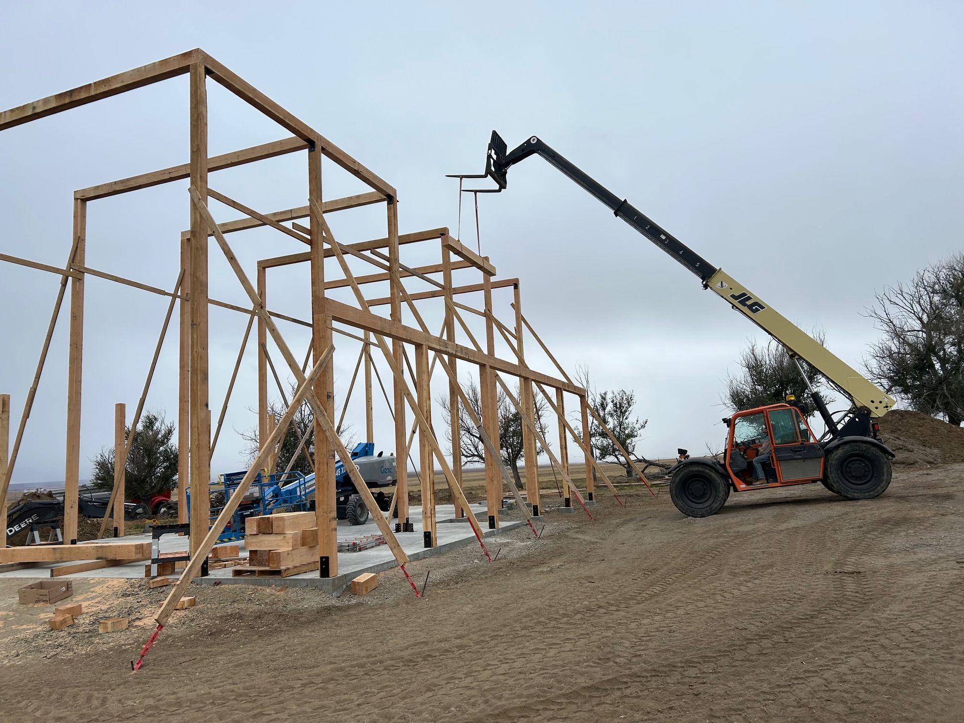 A crane is lifting a wooden structure in a dirt field.