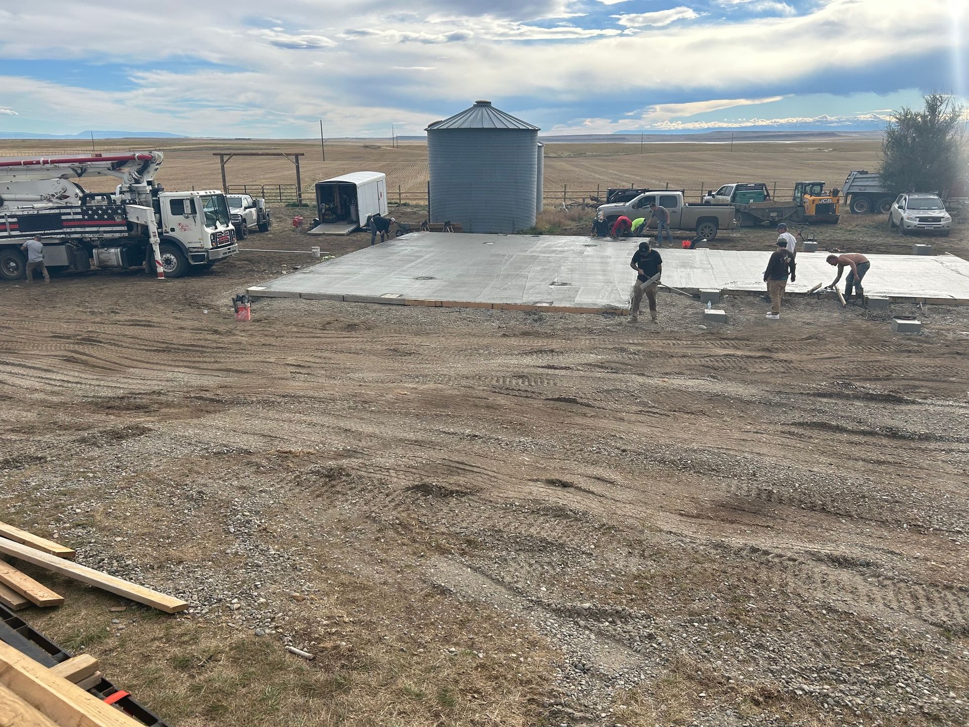 A group of people are working on a concrete slab in a dirt field.