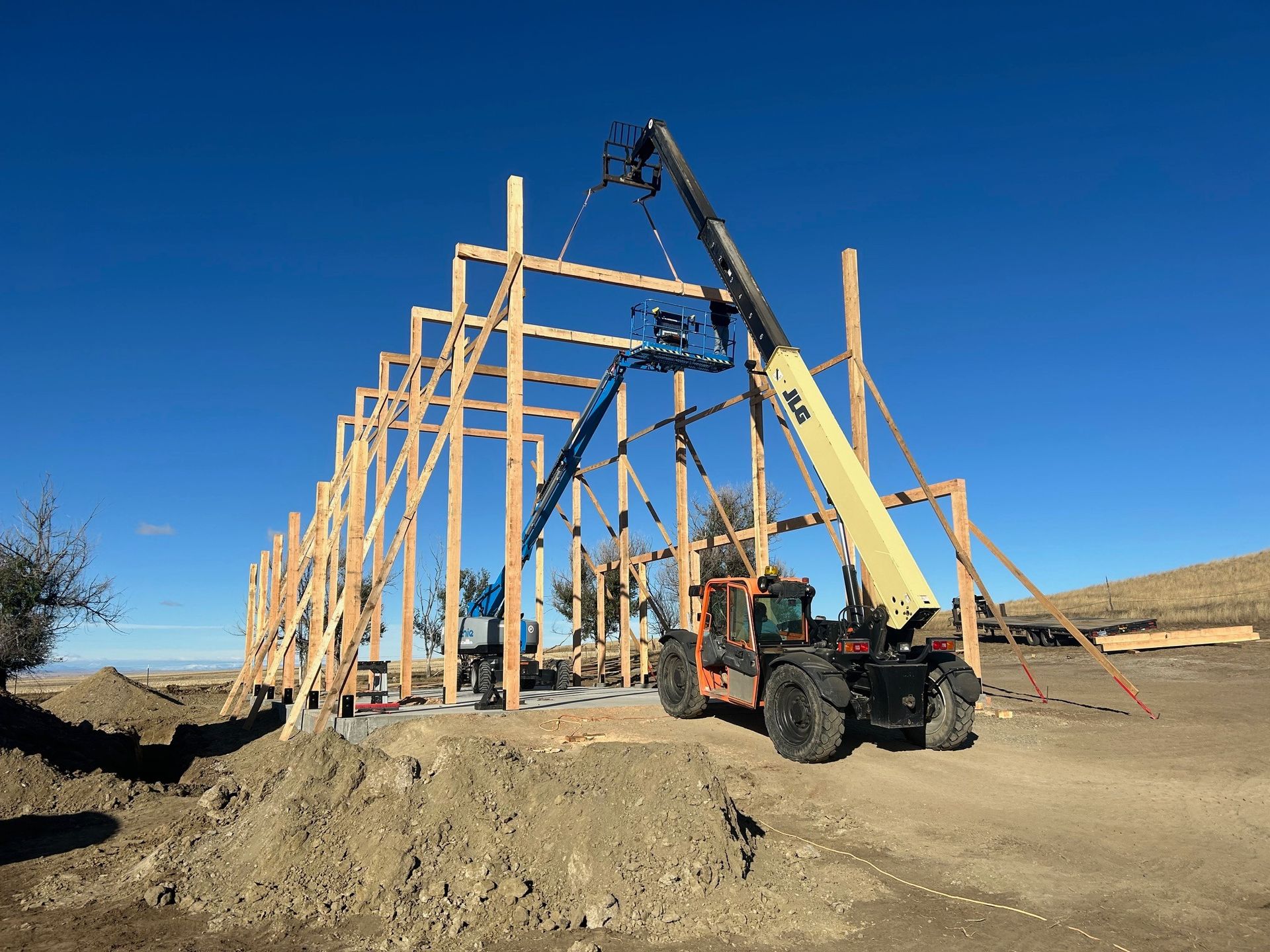 A forklift is lifting a wooden structure in the dirt.