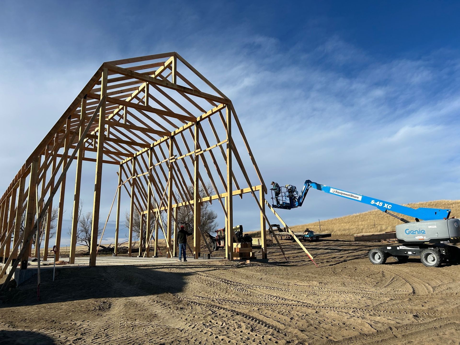 A large wooden structure is being built in a dirt field.