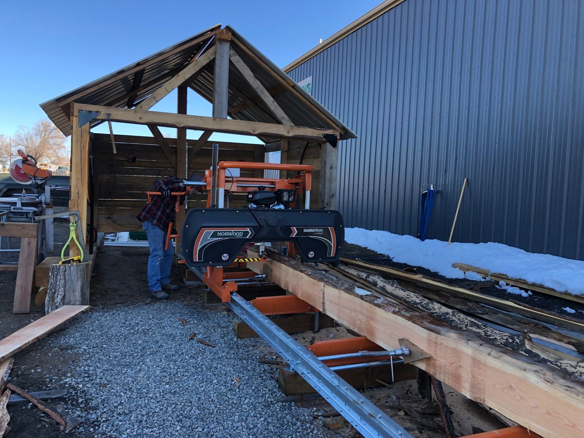 A man is standing next to a machine that is cutting a piece of wood.