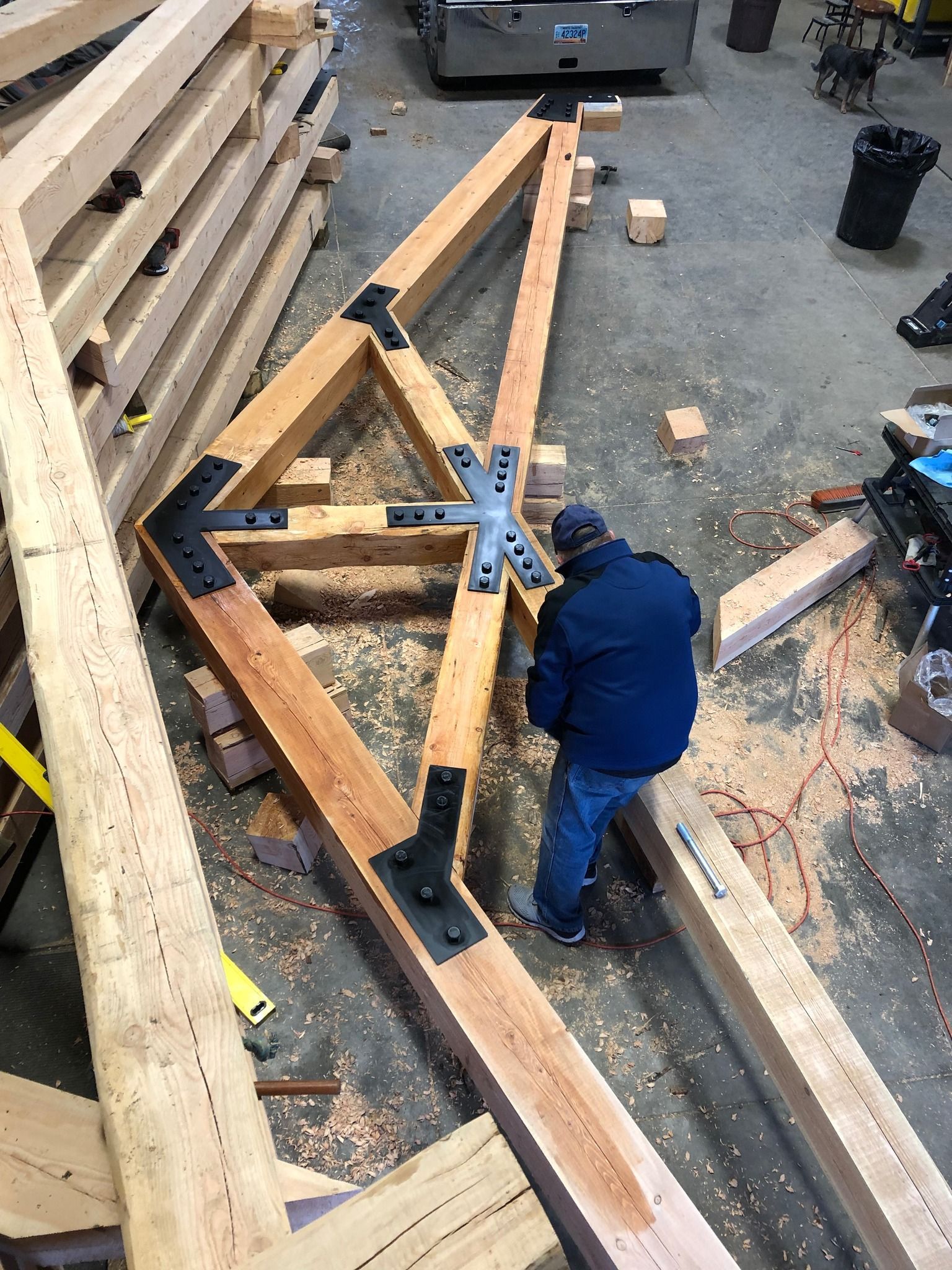 A man is working on a wooden structure in a workshop.