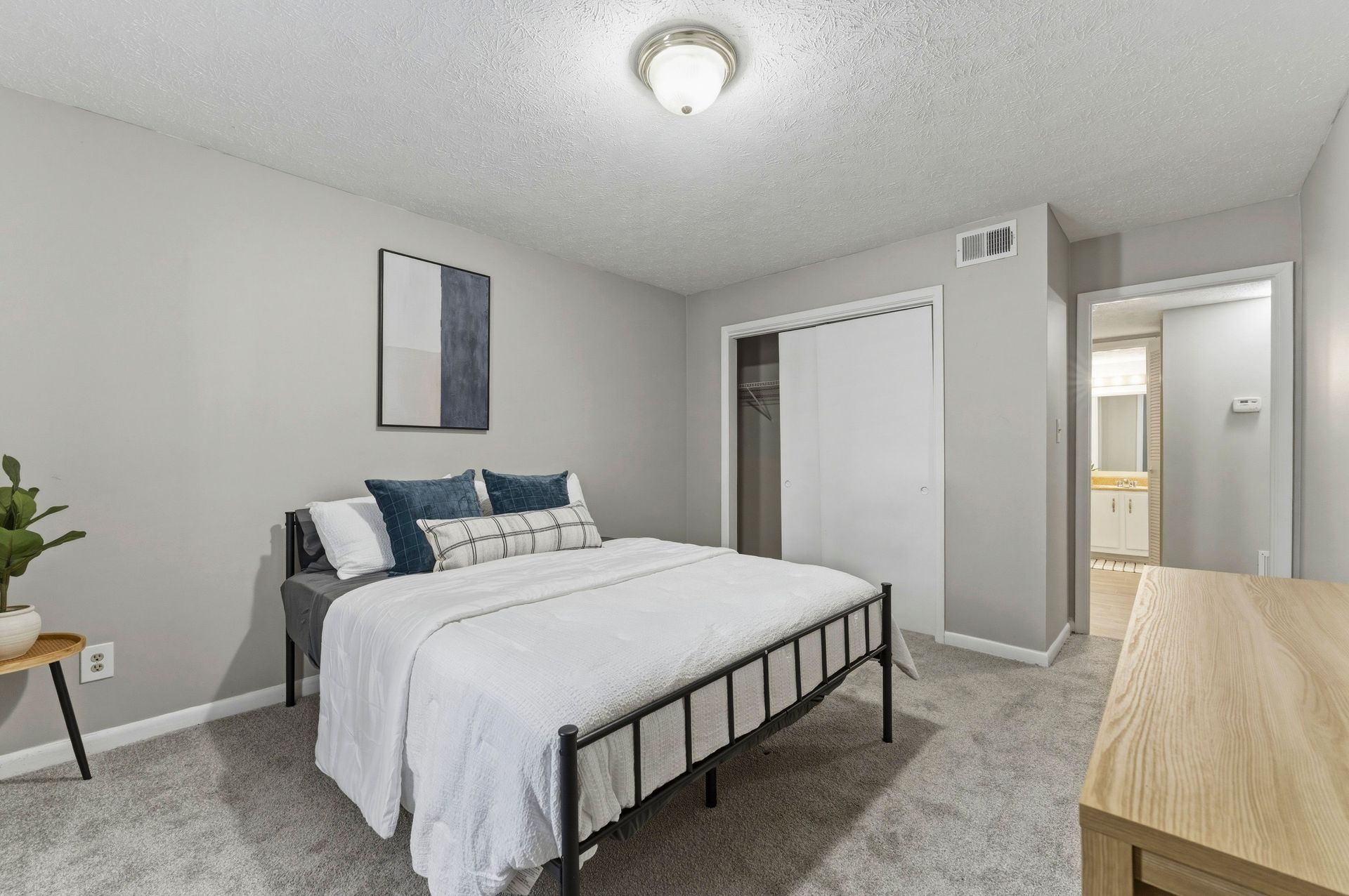 Bright bedroom with a bed, dresser, mirrored closet, and open door to a hallway