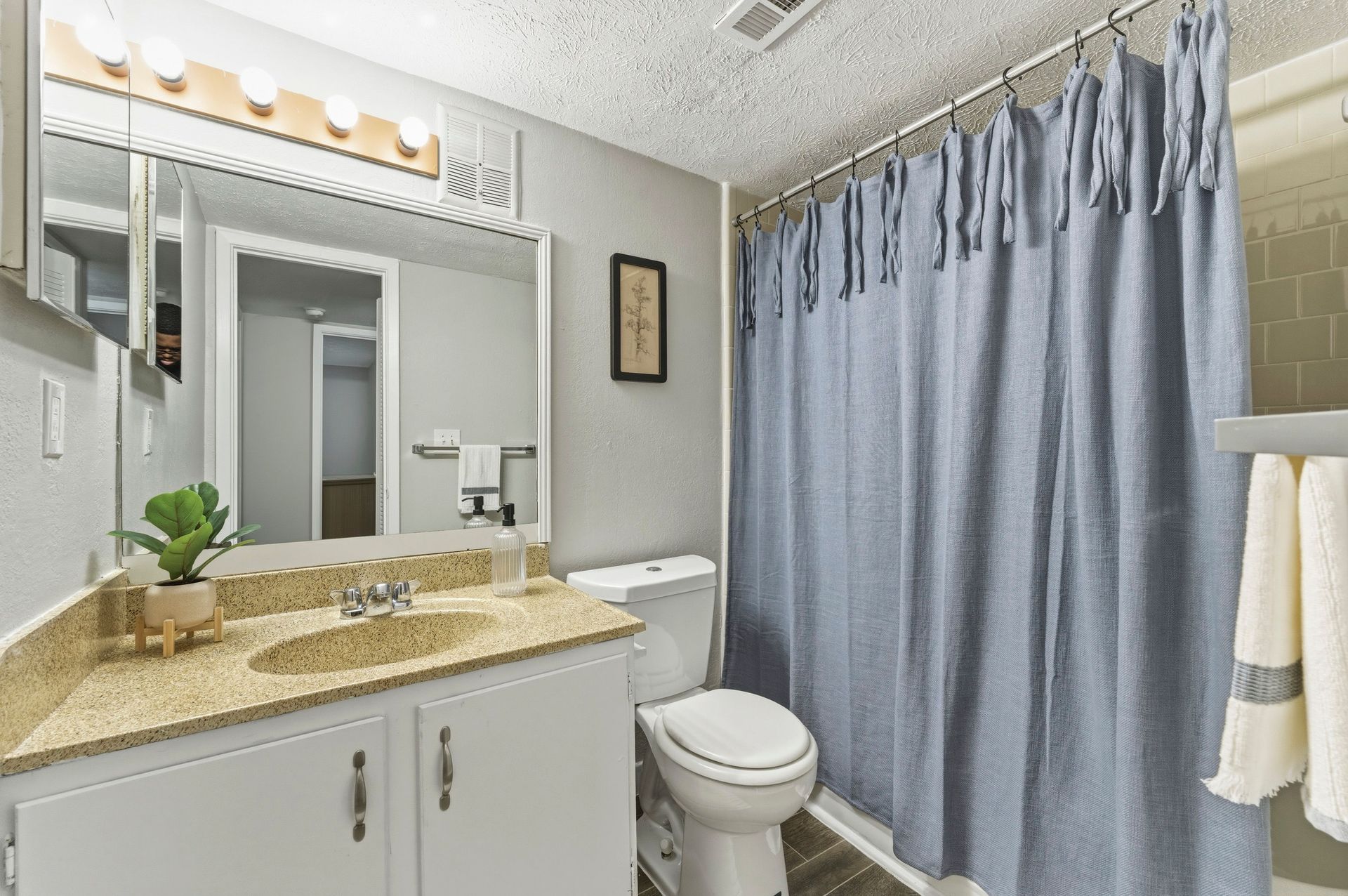 Small bathroom with vanity, mirror, toilet, and blue shower curtain