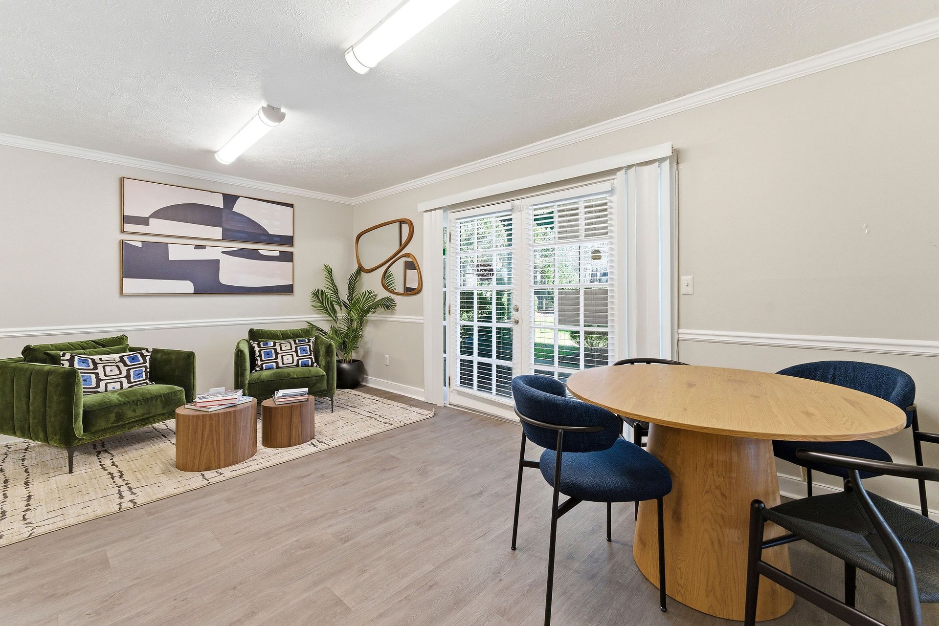 Bright living room with green sofas, round dining table, and sliding glass doors to a patio