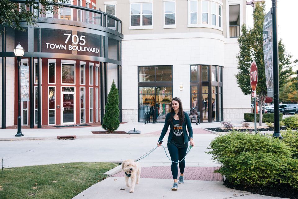 Woman walking a small dog on a leash outside 705 Town Blvd building