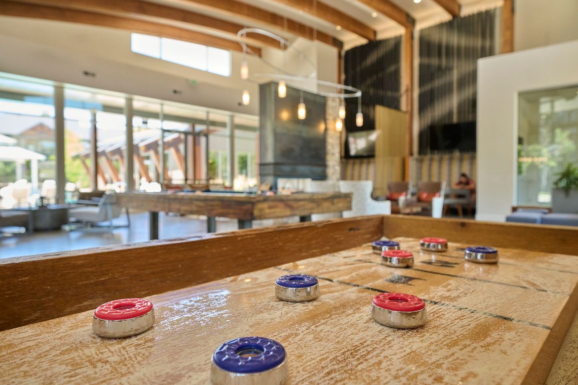 Shuffleboard table with red and blue pucks — The District at Parkcenter