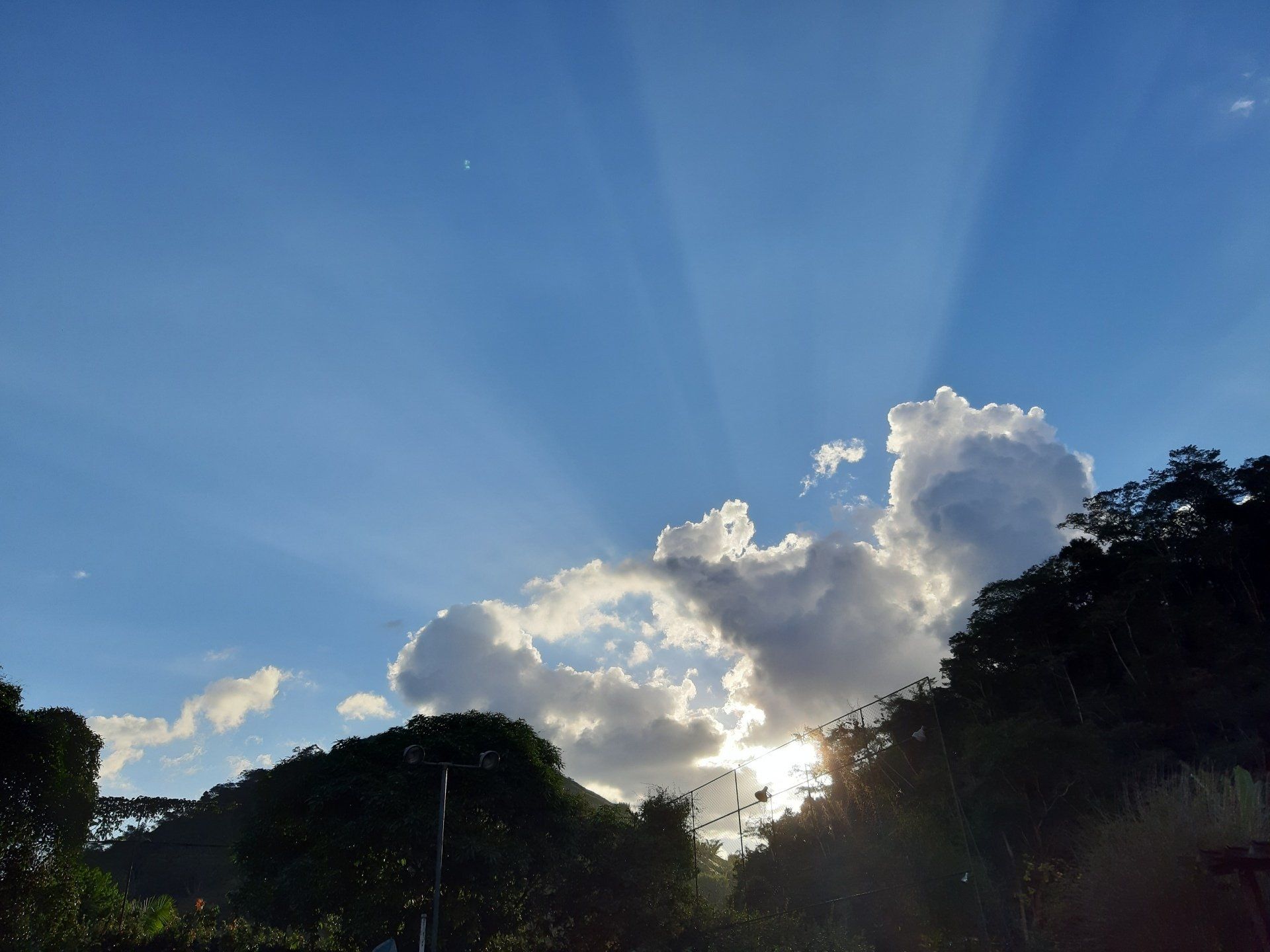 Lindo céu azul e raios de sol entre nuvens ao entardecer. 