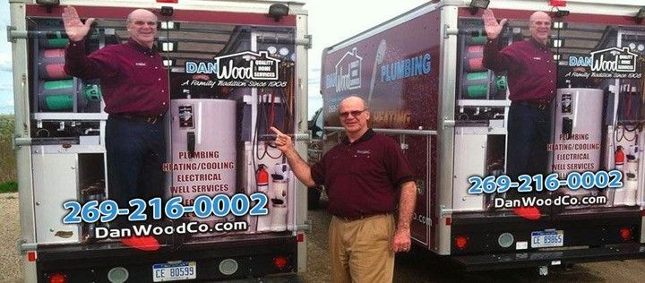 A man standing in front of two trucks that say dan wood co.