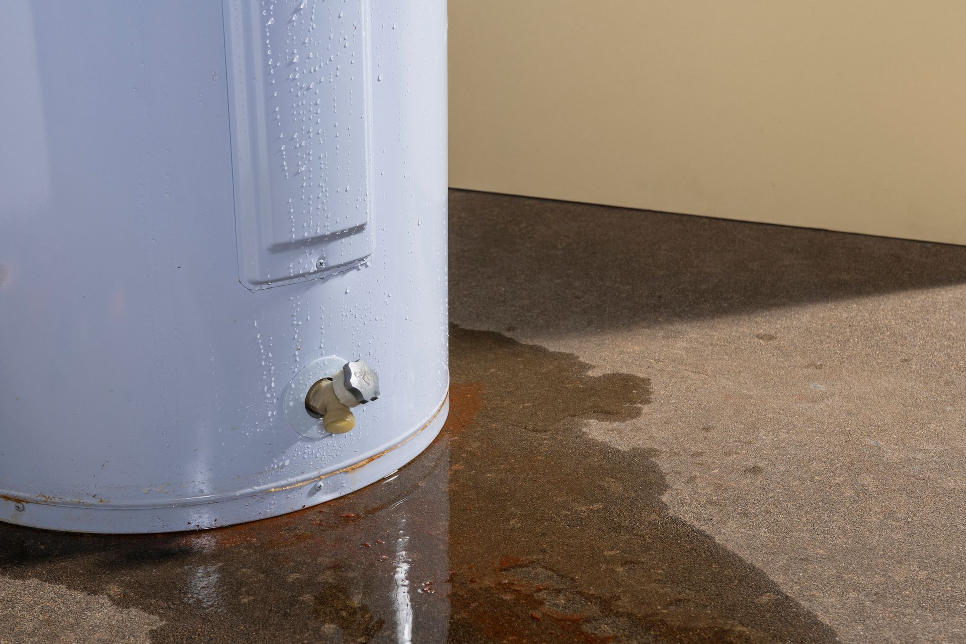 Old water heater showing visible rust and leaking water.