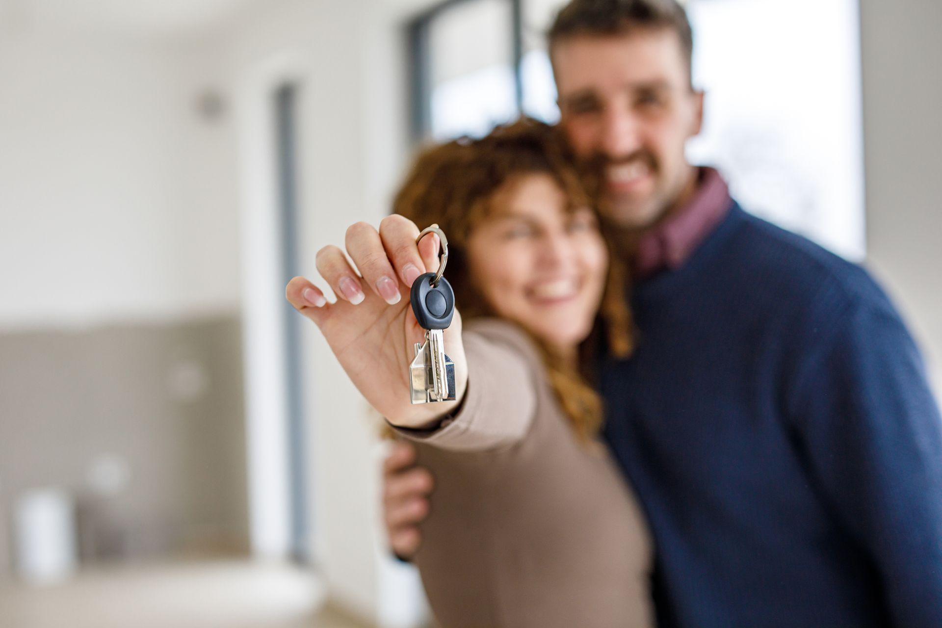 A man and a woman are holding keys to their new home.