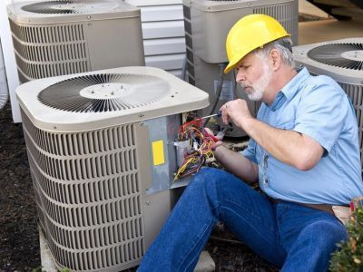 Man Repairing HVAC Unit — Portage, MI — Dan Wood Company Man Repairing HVAC Unit — Portage, MI — Dan Wood Company