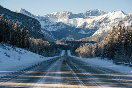 A snowy highway with mountains in the background.