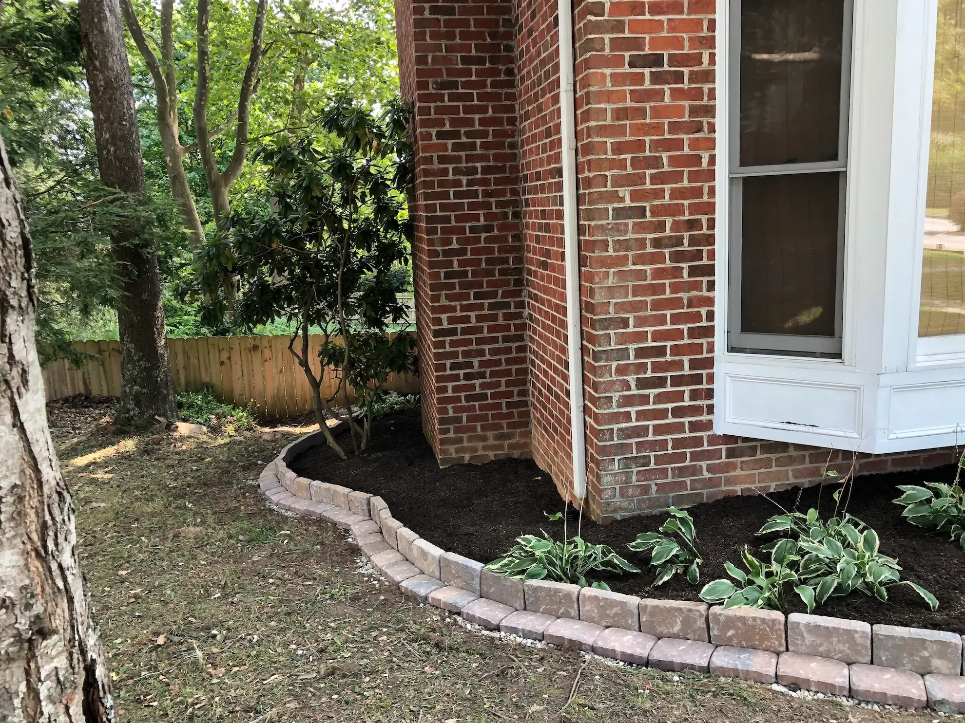 A brick house with a large bay window and a garden in front of it.