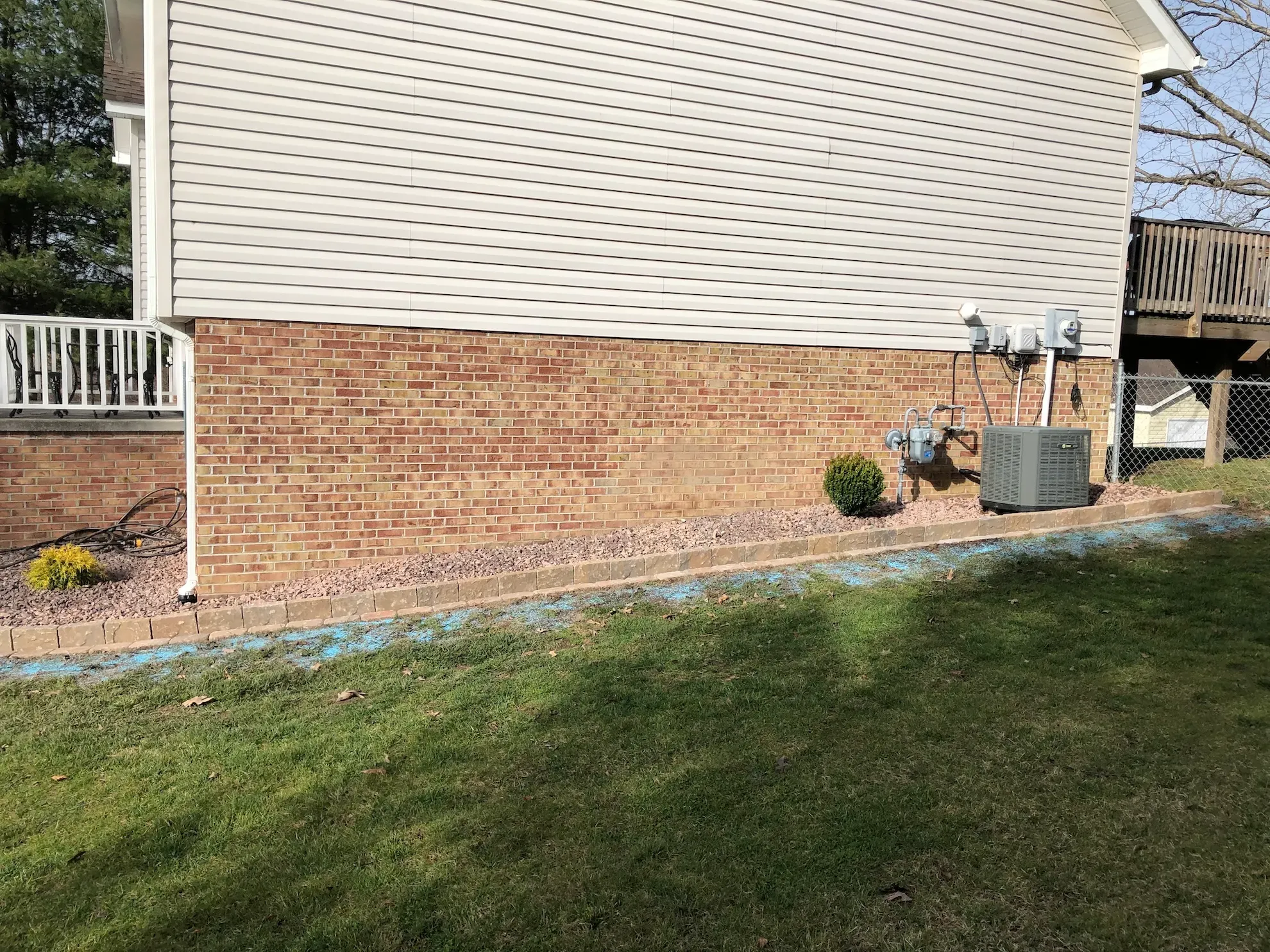 A brick house with a white siding and a lawn in front of it.