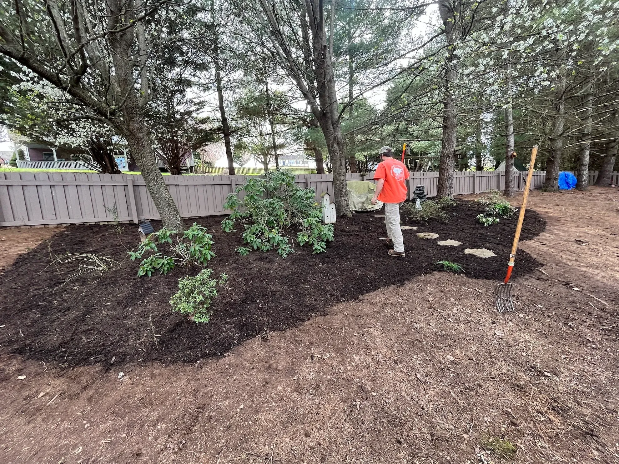 A man is standing in a yard with a shovel.