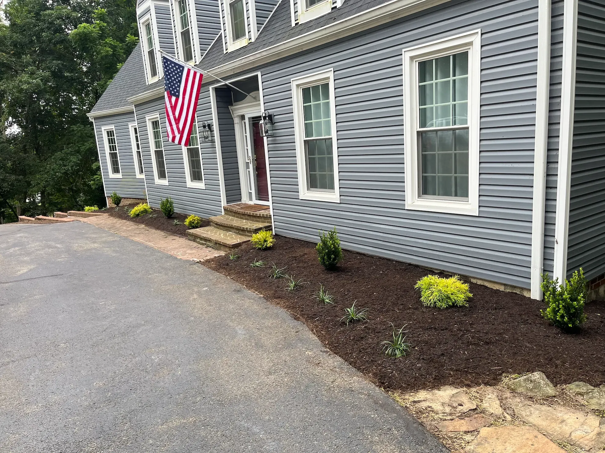 A large gray house with a large american flag hanging from the front of it.
