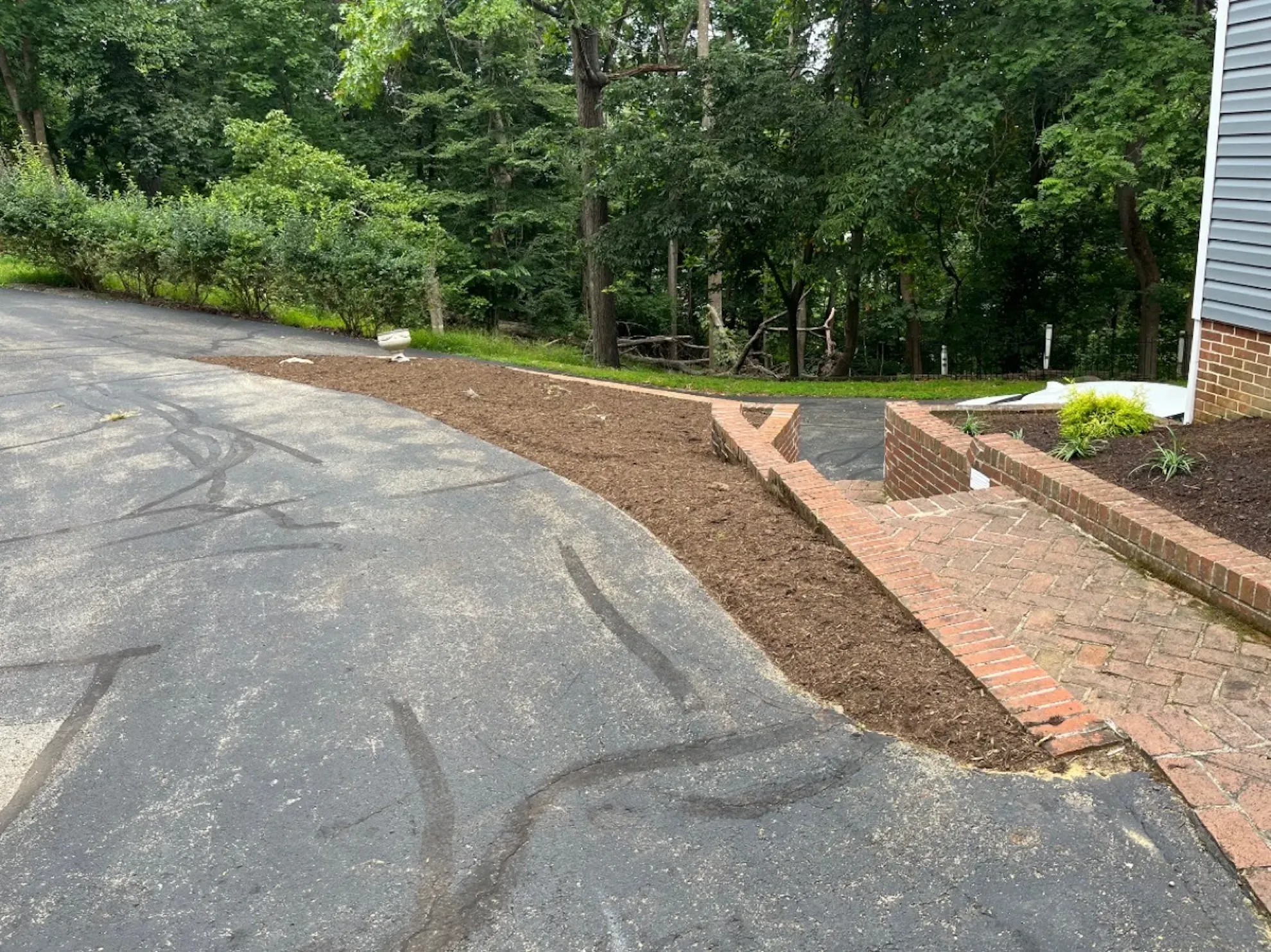 A driveway with a brick walkway leading to a house.