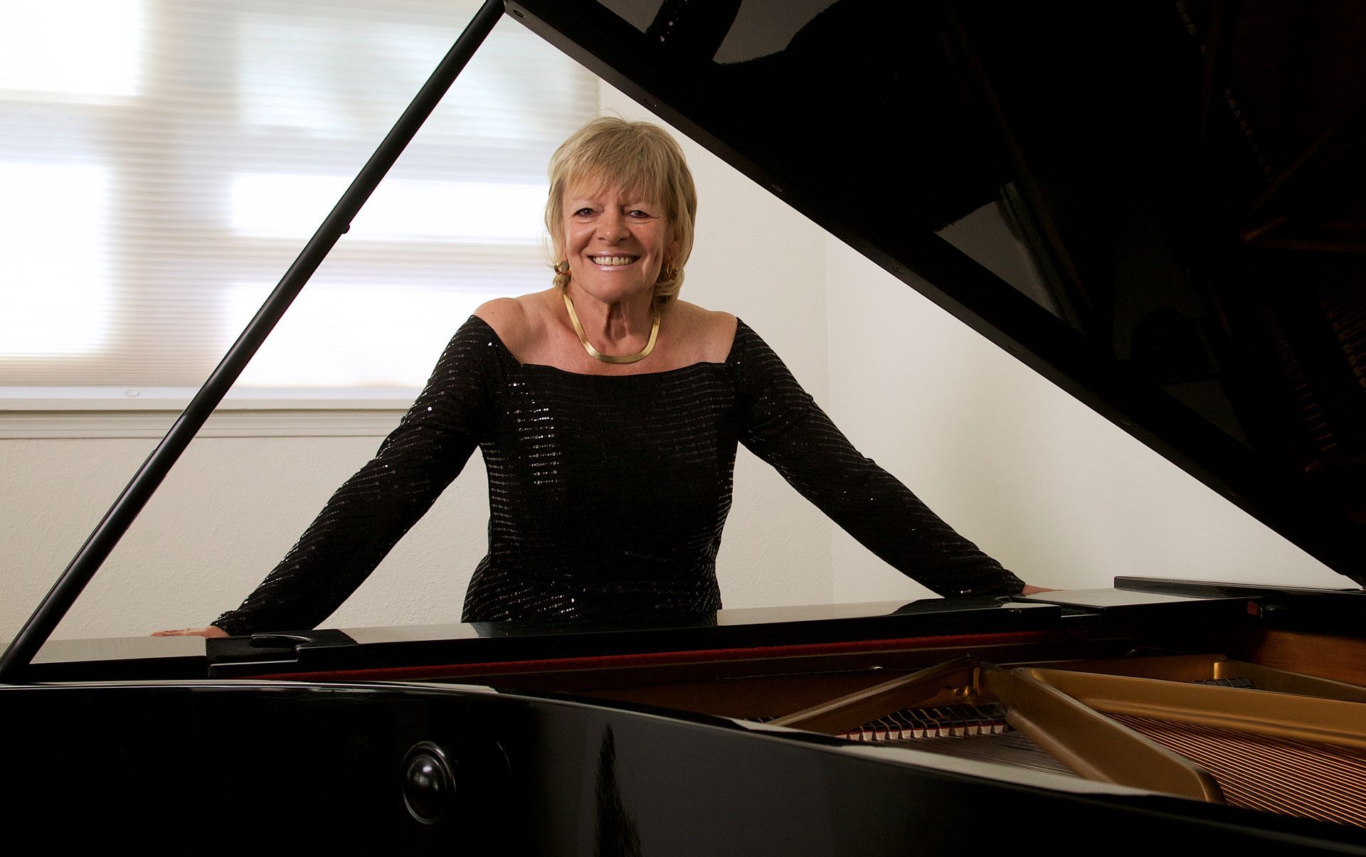 Jacquelyn Helin standing behind a piano wearing a black sequin dress.