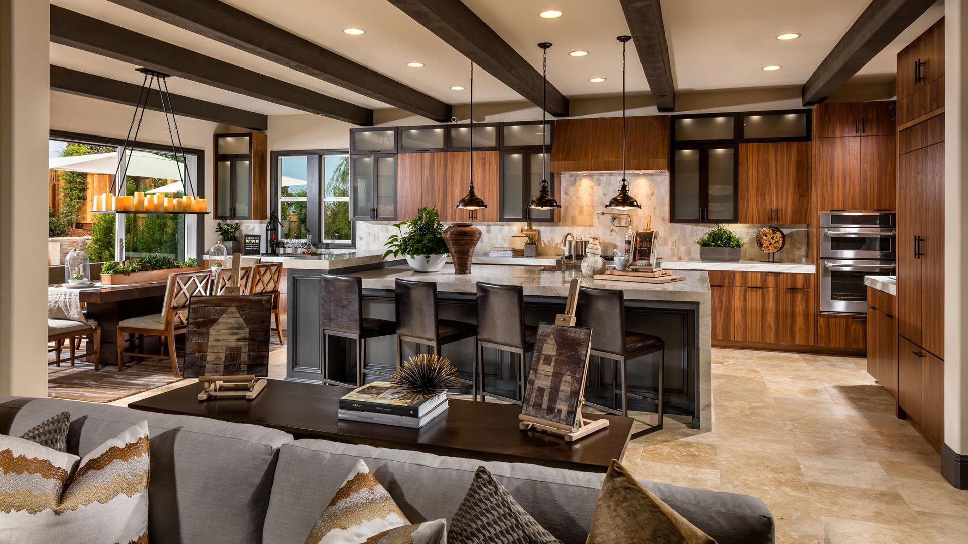 Open-plan modern kitchen and living room with dark wood cabinets, island seating, and warm lighting.