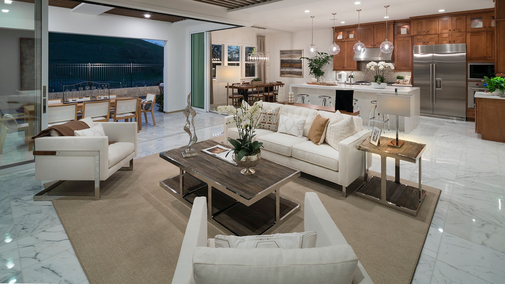 Modern open-plan living room and kitchen with white sofas, marble floor, and wood-accent cabinets